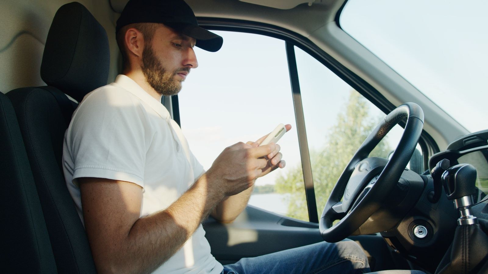A phone showing a locked app screen resting on a car dashboard in daylight