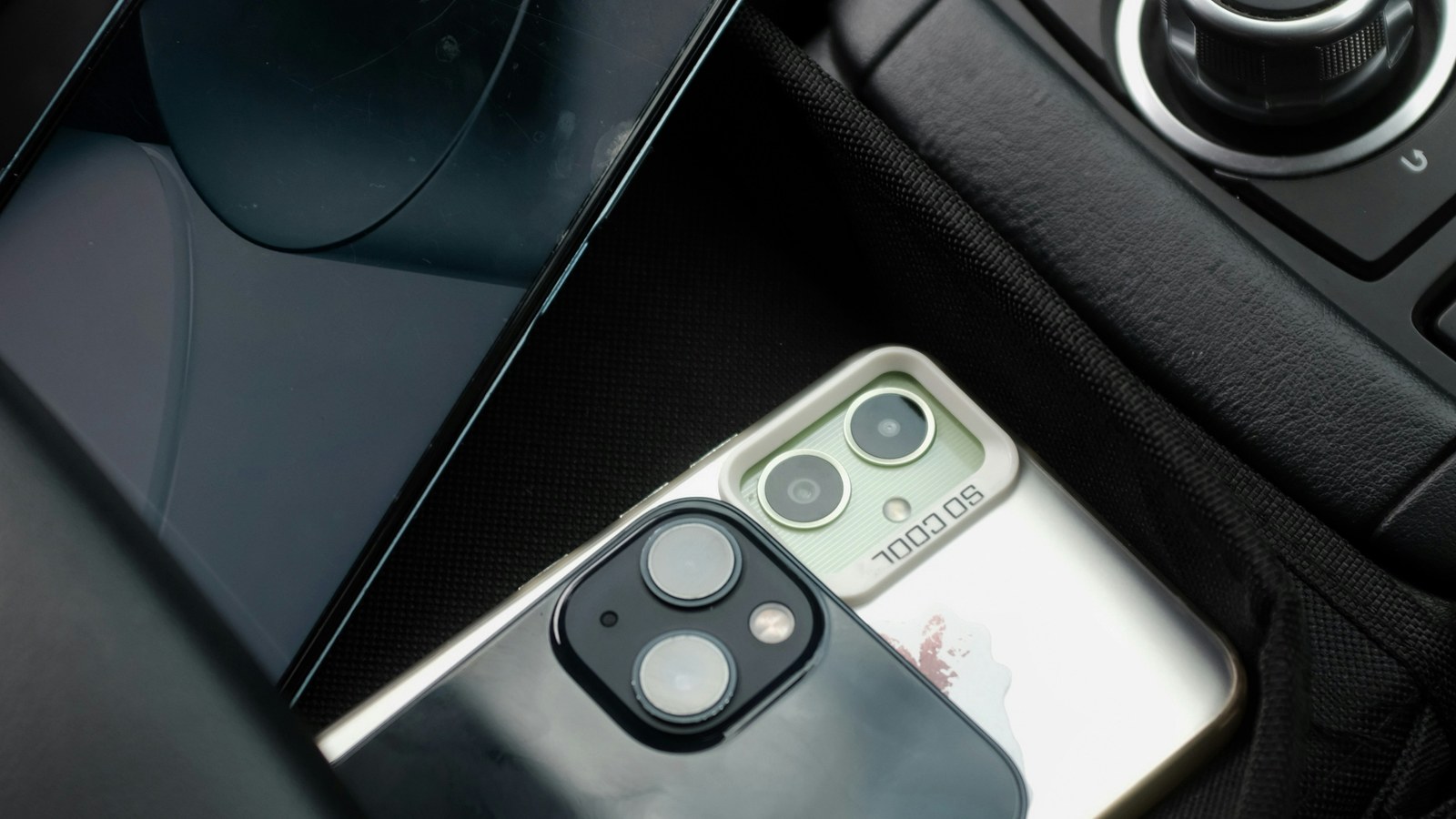 Two phones in dashboard mounts in a parked car, one showing a map