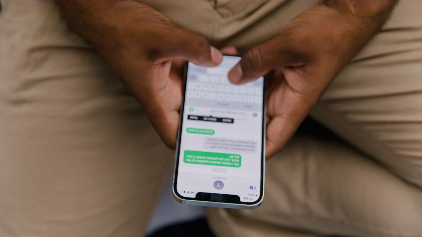 A phone held in one hand in a warehouse aisle, a message half typed